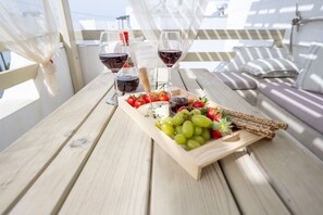 Una mesa de madera con una tabla de quesos, uvas, fresas y copas de vino.