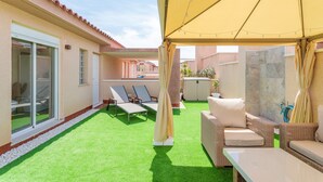 Una zona exterior coberta amb gespa artificial, gandules i una taula.