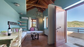 A room with a wooden table, a bench, a wine bottle, and a view of the sea. - Apartment 'Kymothoi' with Sea View, Wi-Fi and Air Conditioning (Ithaca)