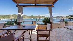 A terrace with a table and chairs, a pergola, and a view of the sea and hills. - Apartment 'Kymothoi' with Sea View, Wi-Fi and Air Conditioning (Ithaca)
