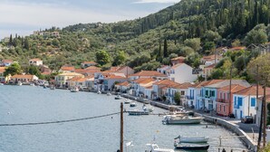 A coastal town with buildings along the waterfront, boats docked, and a hilly backdrop. - Apartment 'Kymothoi' with Sea View, Wi-Fi and Air Conditioning (Ithaca)