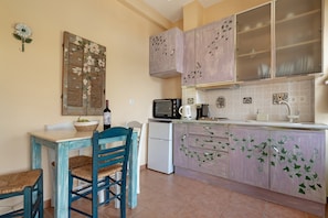 Cuina amb taula de menjador, cadires, nevera, microones i armaris decorats amb motius de vïta.