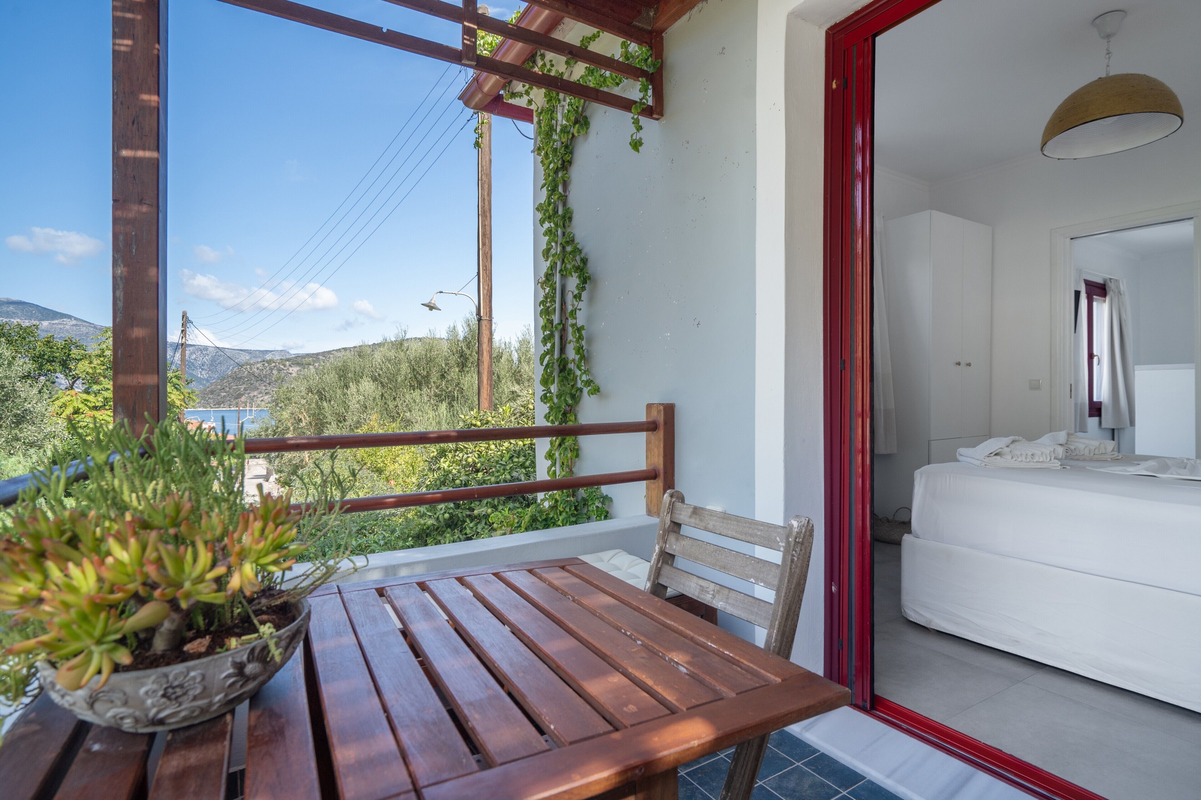 Un balcon avec une table et une chaise en bois, un pot de fleurs et une vue sur les montagnes.