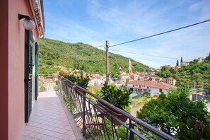 A balcony with a view of a town, a church, and a hill.