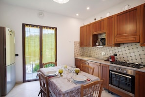 Une cuisine avec des meubles de rangement en bois, une cuisinière et une table à manger pour quatre personnes.