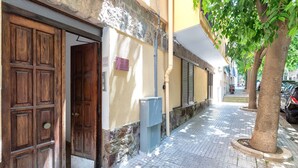 A street with a wooden door, a utility box, and a tree. - Apartment 'Attico 29 Alghero' with Balcony, Wi-Fi and Air Conditioning (Alghero)