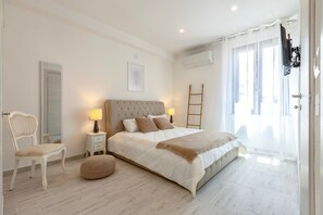 Une chambre à coucher avec un lit, des tables de chevet, une chaise, une échelle et une fenêtre avec des rideaux.