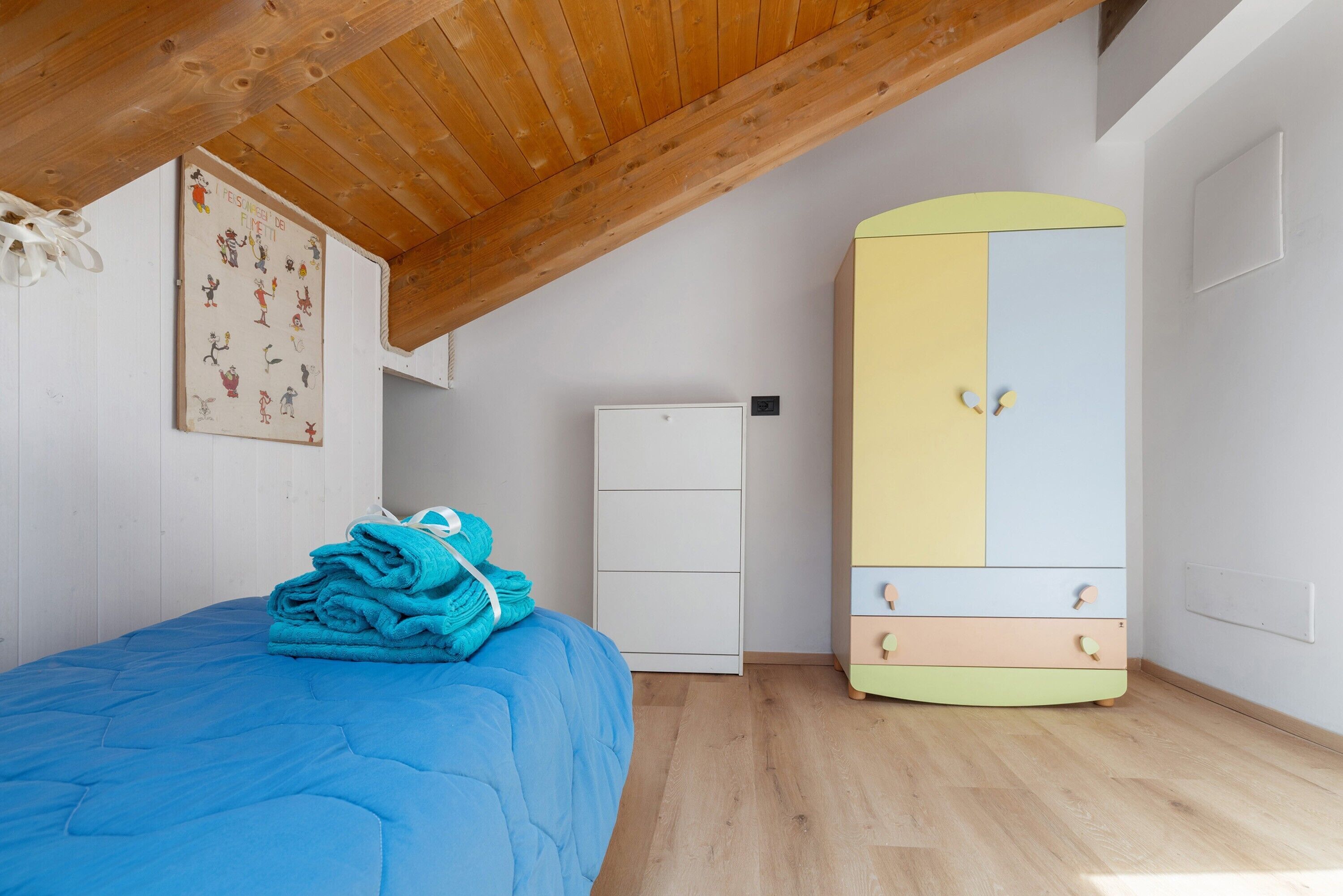 A bedroom with a bed, a wardrobe, and a wall with a poster.