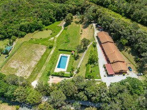 An aerial view of a property with a swimming pool, a large building with a red roof, and surrounding greenery. - Apartment 'Erba Di Campo - Patata' with Shared Pool, Wi-Fi and Air Conditioning (Livorno)