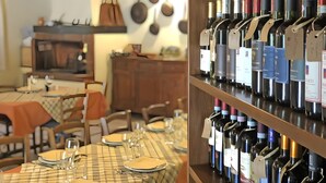 A restaurant interior with a dining area, a wine rack with various bottles, and a kitchen in the background. - Apartment 'Malva' with Shared Pool, Wi-Fi and Air Conditioning (Livorno)