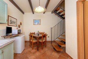Una cocina con una mesa de comedor, sillas, un microondas y una computadora en un estante.