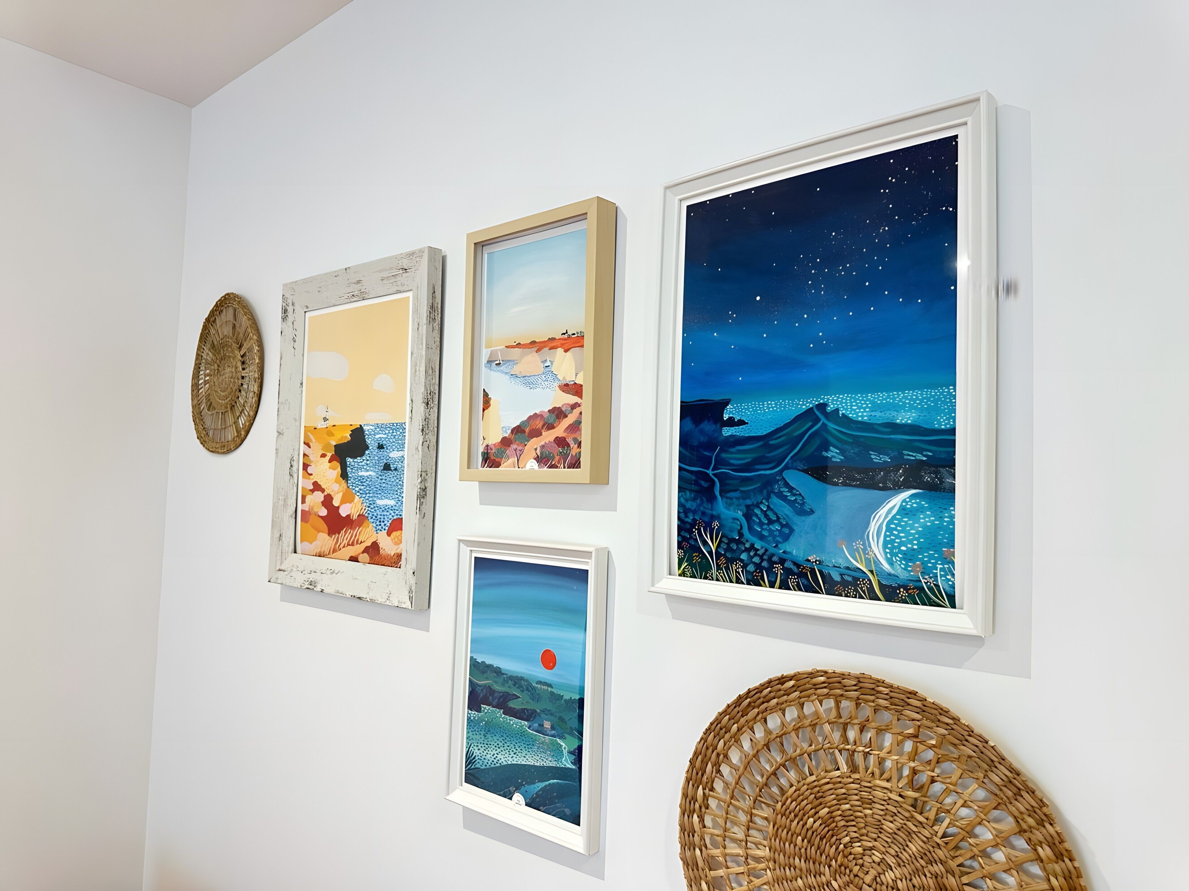 A wall with four framed artworks and a woven basket.