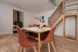 A dining area with a wooden table and chairs, a staircase, and a fireplace.