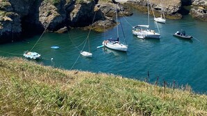 A coastal landscape with rocky terrain, a clear sky, and several boats anchored in a calm bay. - Ker mam - Belle-Île en Mer, electric bikes at your disposal (Sauzon)