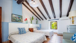 Ein Zimmer mit zwei Betten, einem Schlafsofa, einem Bild, einem Fenster und einer Decke mit sichtbaren Balken.