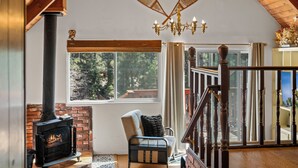 A cozy room with a fireplace, a comfortable chair, and a staircase leading to an upper level.