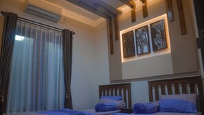 Une chambre avec deux lits, une grande fenêtre avec des rideaux, un appareil de climatisation et des œuvres d’art accrochées au mur.