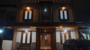 Un bâtiment à deux étages avec un escalier central, une voiture garée devant et une enseigne au-dessus de l’entrée.