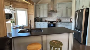 Een moderne keuken met een centraal eiland, roestvrijstalen apparatuur en lichtkleurige kastjes.
