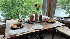 Een eettafel met eten, kruiden en een vaas met bloemen.