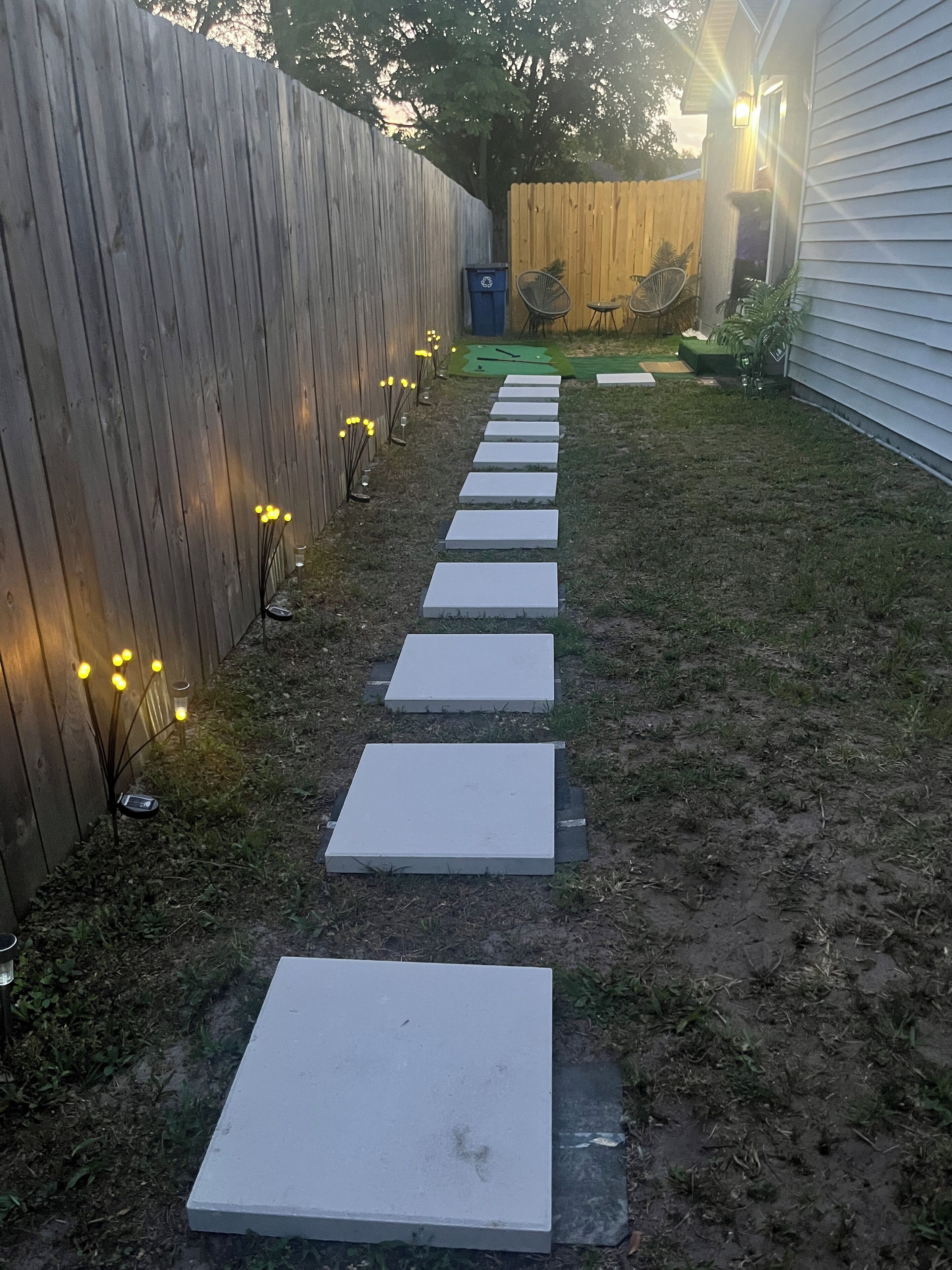 Un sentier de jardin avec des marches menant à une clôture en bois.