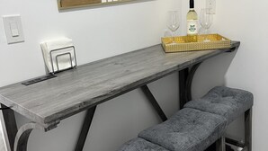 A dining area with a long wooden table, two benches, a wall-mounted decorative piece, and a tray with a bottle and glasses. - Cozy Private Tiny Guest House (Jacksonville)