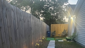 A wooden fence, a pathway with stepping stones, and a small garden area with a bench and chairs. - Cozy Private Tiny Guest House (Jacksonville)
