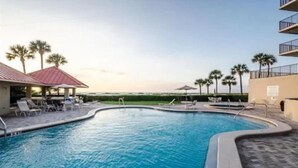 A swimming pool with lounge chairs and a view of the ocean.
