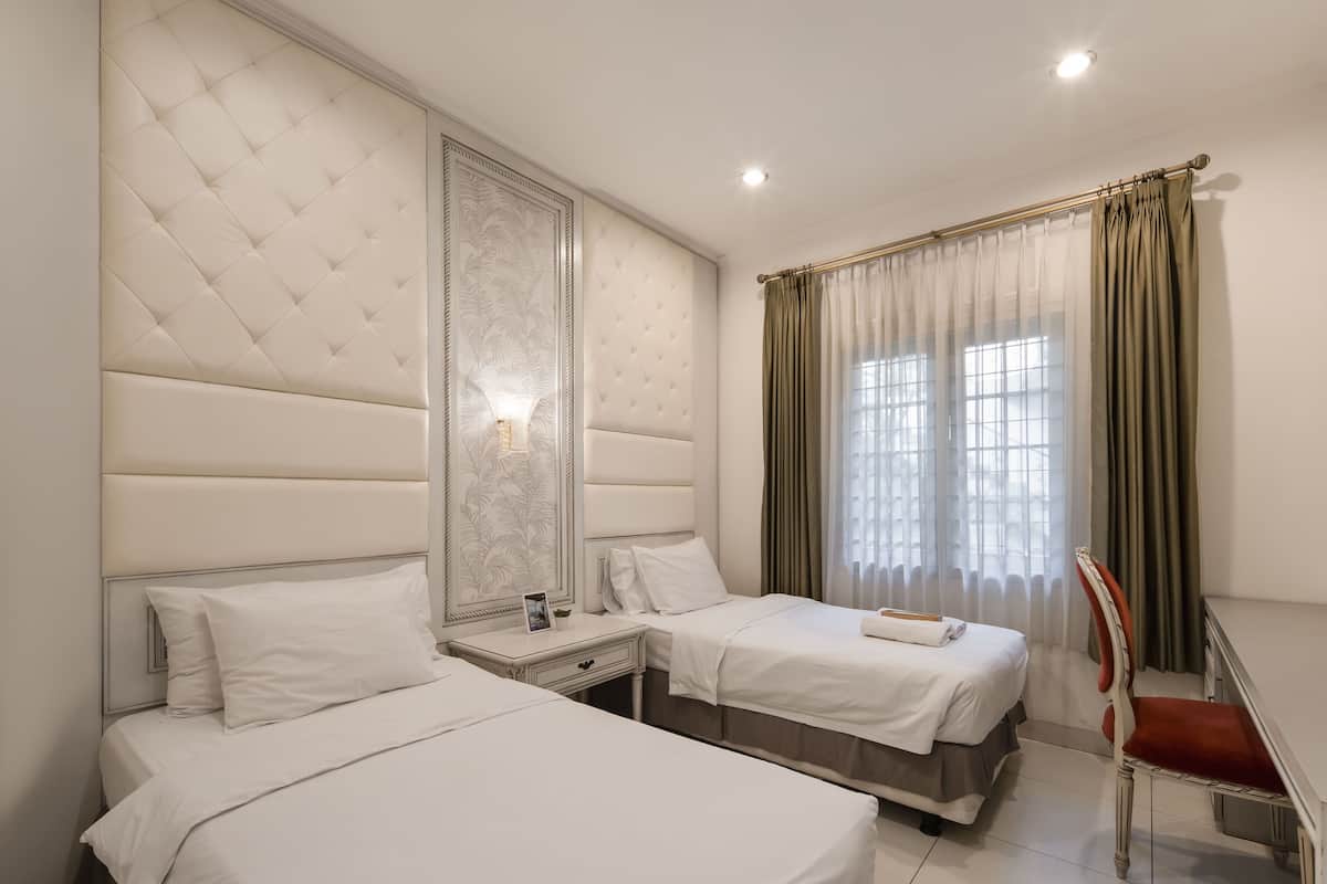 A hotel room with two beds, a large mirror, a desk, and a chair.