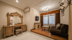 A living room with a wooden vanity, a television, a sofa, and a chandelier.