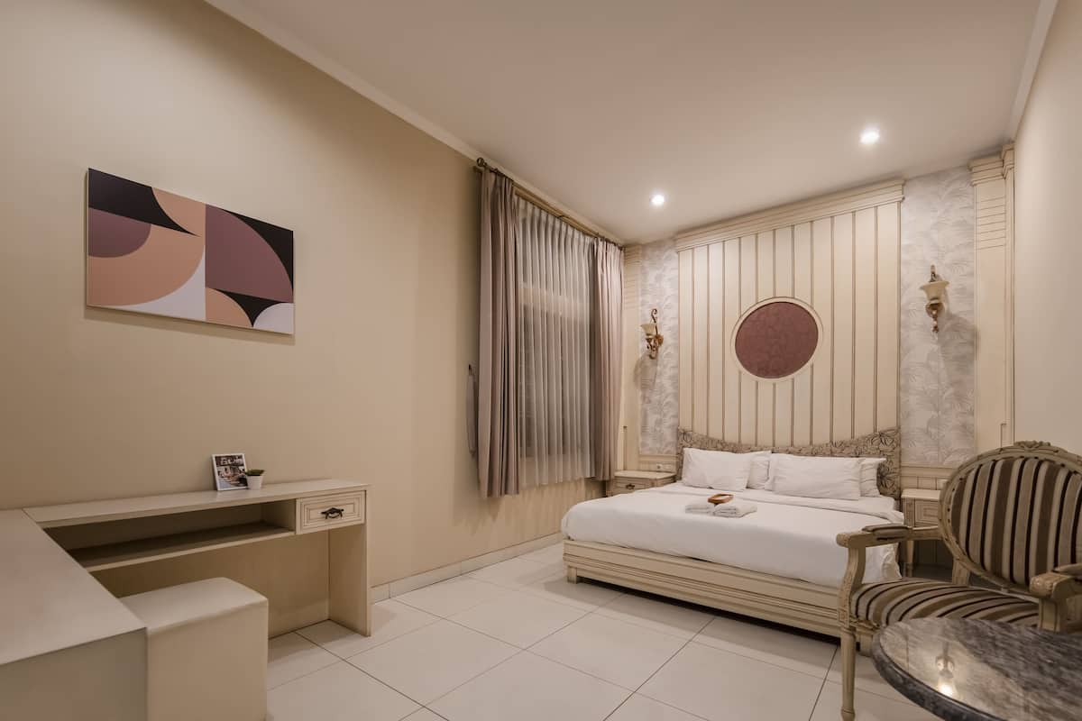 A bedroom with a bed, a desk, a chair, and a wall-mounted artwork.
