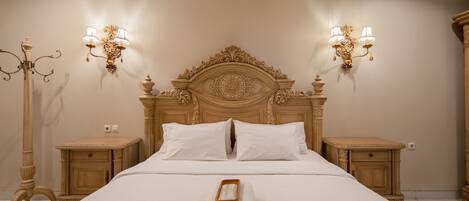 A neatly made bed with white linens, two bedside tables with lamps, and a decorative wall sconce.