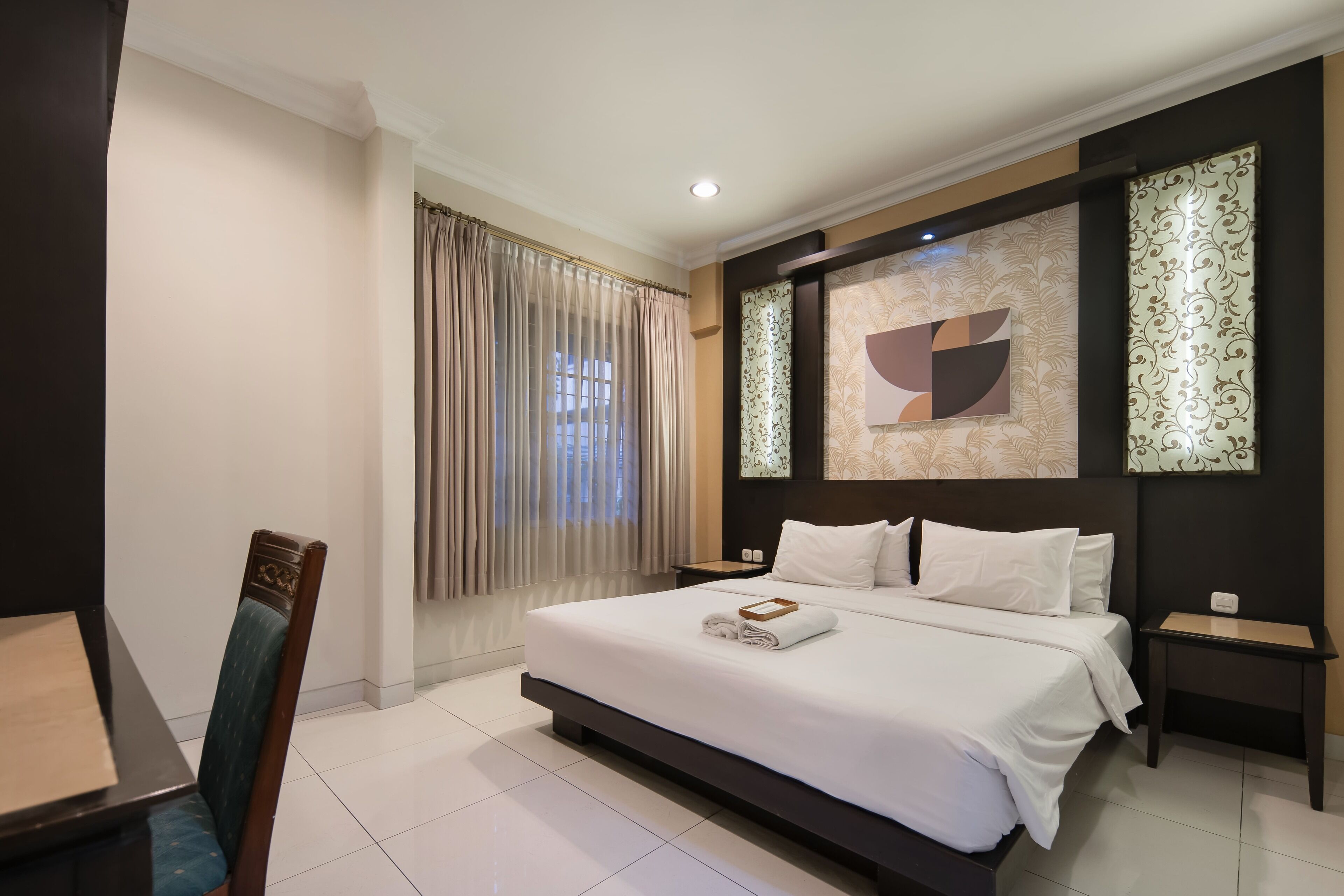 A modern hotel room with a large bed, a dining table, and a chair.
