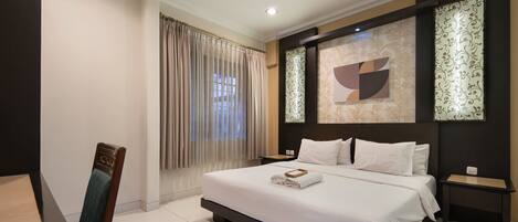 A modern hotel room with a large bed, a dining table, and a chair.