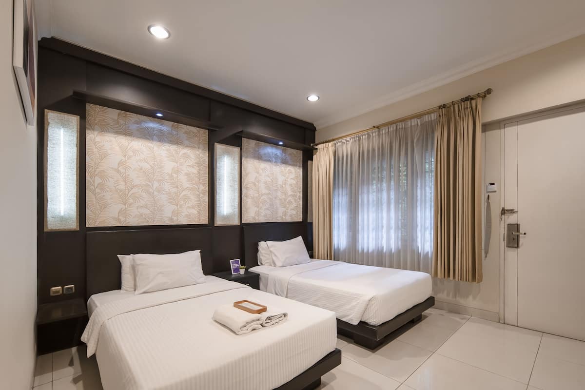 A hotel room with two beds, a large window with curtains, and a modern design.