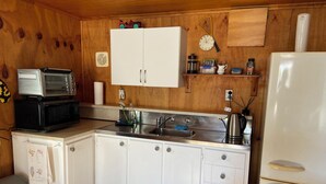 A compact kitchen with white cabinets, a stainless steel sink, a white refrigerator, and a microwave. - Cozy, comfortable and close to CBD (Whakatane)