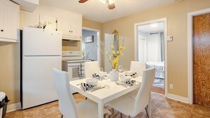 Una cocina moderna con armarios blancos, horno empotrado y una mesa de comedor preparada para cuatro comensales.