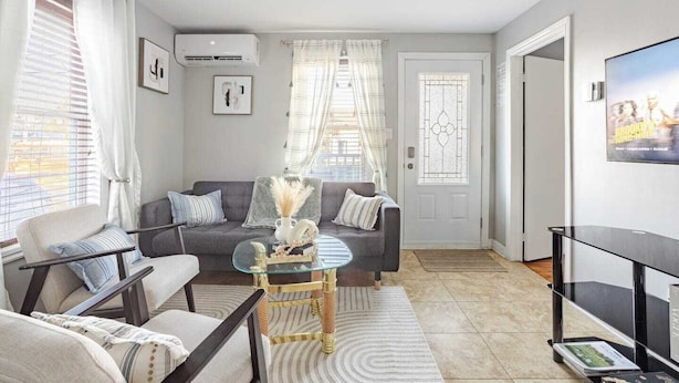 A modern living room with a grey sofa, a glass coffee table, and a TV stand.