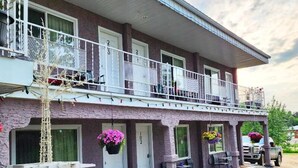 A two-story building with a balcony, a porch with outdoor seating, and a truck parked outside. - Athabasca Hillside Motel (Athabasca)