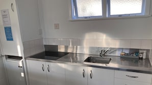 Une cuisine moderne dotée d’appareils électroménagers en acier inoxydable, d’un évier à deux bacs et de meubles blancs.