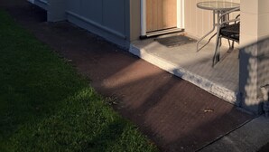 Une rangée de bâtiments d’un seul étage, dotés d’un toit plat, d’un petit espace extérieur avec une table et des chaises, et d’une porte portant le numéro 8.