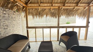 Un espace extérieur abrité, doté d’un sol en pierre, de poutres en bois et d’un toit en chaume.