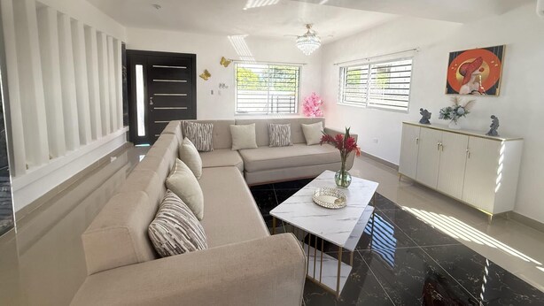 Un salon moderne avec un canapé d’angle beige, une table basse en marbre et un meuble blanc.