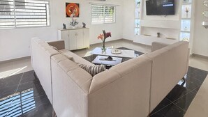 Un salon moderne avec un canapé beige, une table basse et un téléviseur fixé au mur.