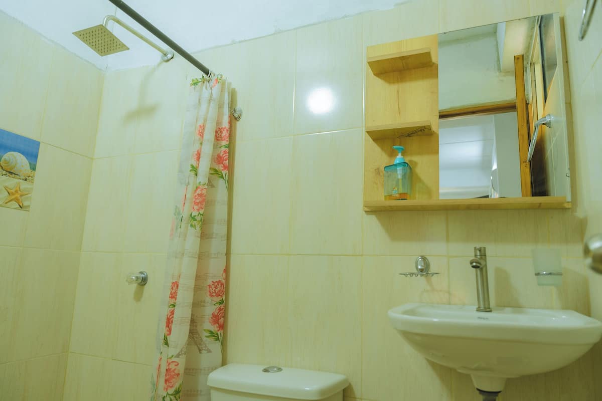 Ein Badezimmer mit Toilette, Dusche, Waschbecken und einem Spiegel über dem Waschbecken.