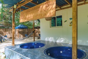 A pool area with two hot tubs, a hammock, and a blue umbrella. - Perla Negra House Hostel Cartagena (Cartagena)