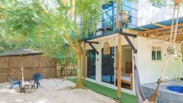 A hotel with a balcony, outdoor seating, and a hammock.