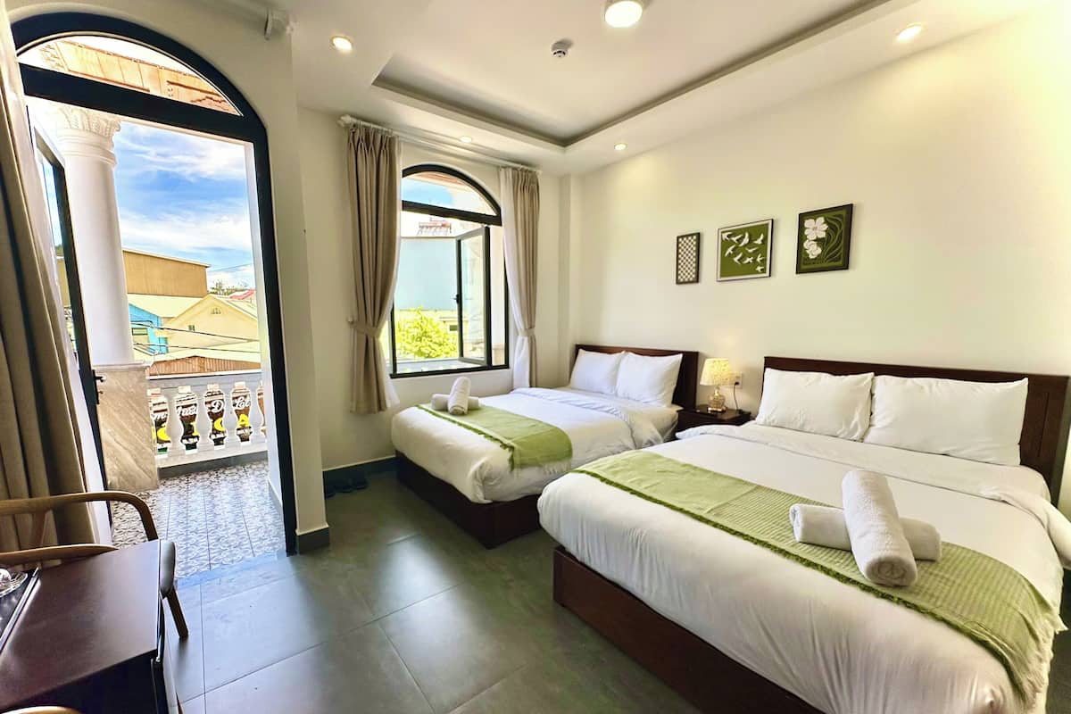 A hotel room with two beds, a balcony, and a view of buildings.