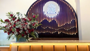 A reception desk with a logo, a floral arrangement, and a modern design with vertical slats. - Amelia House - Boutique Hotel (Lam Vien - Da Lat)