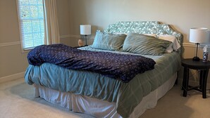 A bedroom with a bed, two bedside tables, a ceiling fan, and a window with blinds.